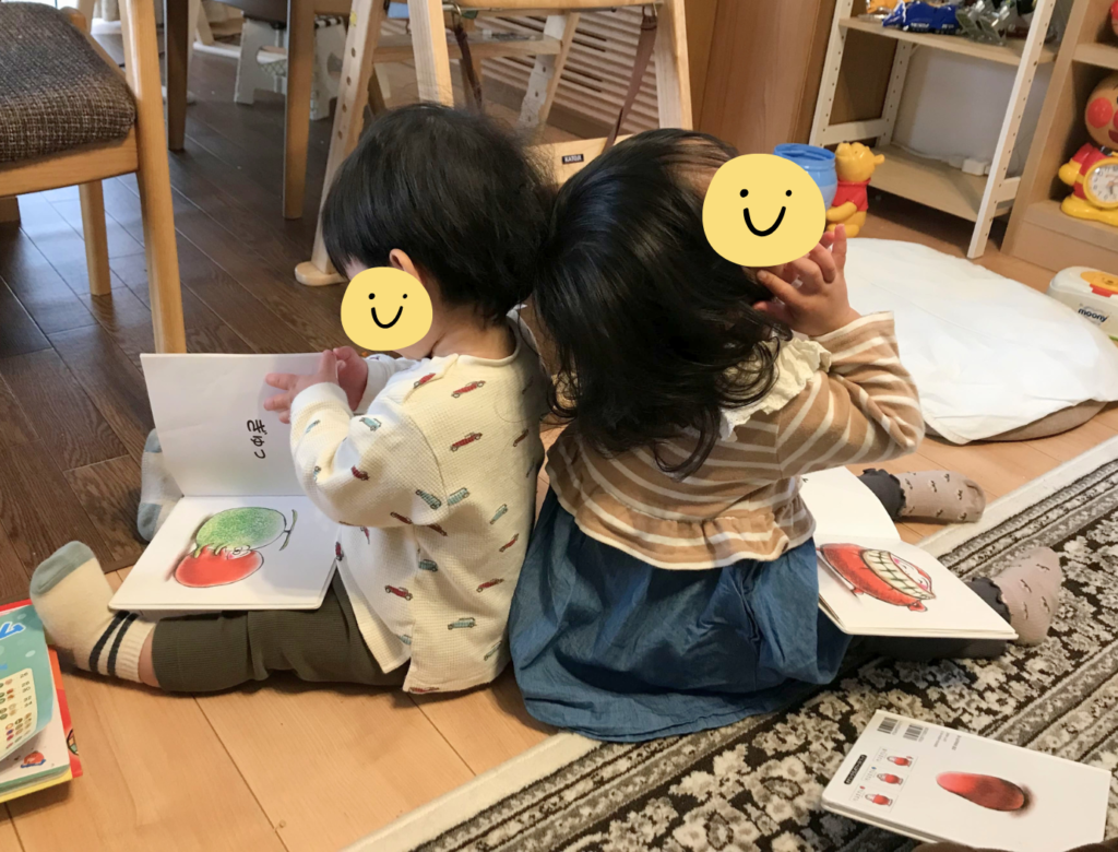 だるまさんシリーズを背中合わせで読む姉弟。絵柄に合わせて手振りを加える三女。読むのに夢中な長男。二人とも当時2、3歳